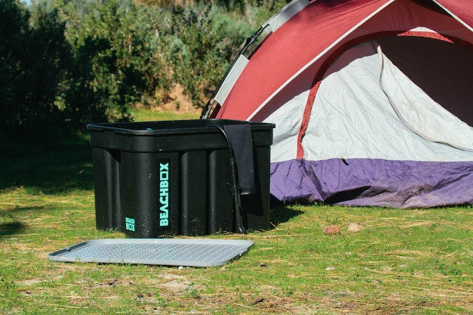 BeachBox storage box and changing mat set up on grass beside a red dome tent