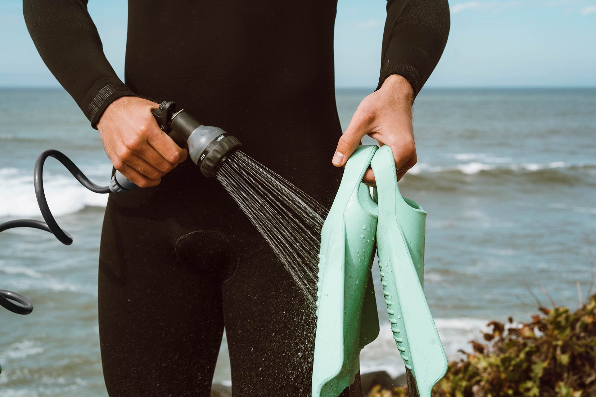 surfer cleaning fins with beachbox portable shower and storage bin